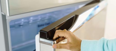 young woman hand opening refrigerator door at home